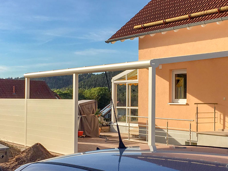 Ein Bild von einem schönen Winergarten mit Feuerholz, Kamin und großzüger Verglasung, durch welche ein Waldstück zu sehen ist.