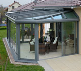 Ein Bild von einem Wintergarten, angebaut an ein Einfamilienhaus mit großzügigem Garten.